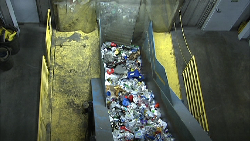 Image of plastic bottles moving through curte at recycling facility.