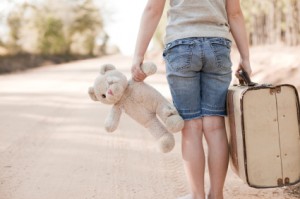 homeless child holding teddy bear and suitcase