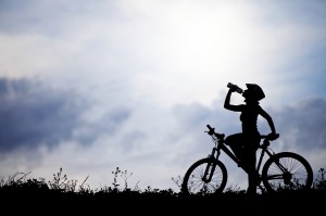Image of woman riding bike stopping to drink water.