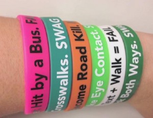 Image of wrist with many braclets with safety messages on them.