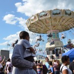 A child watches a ride from his father's shoulders