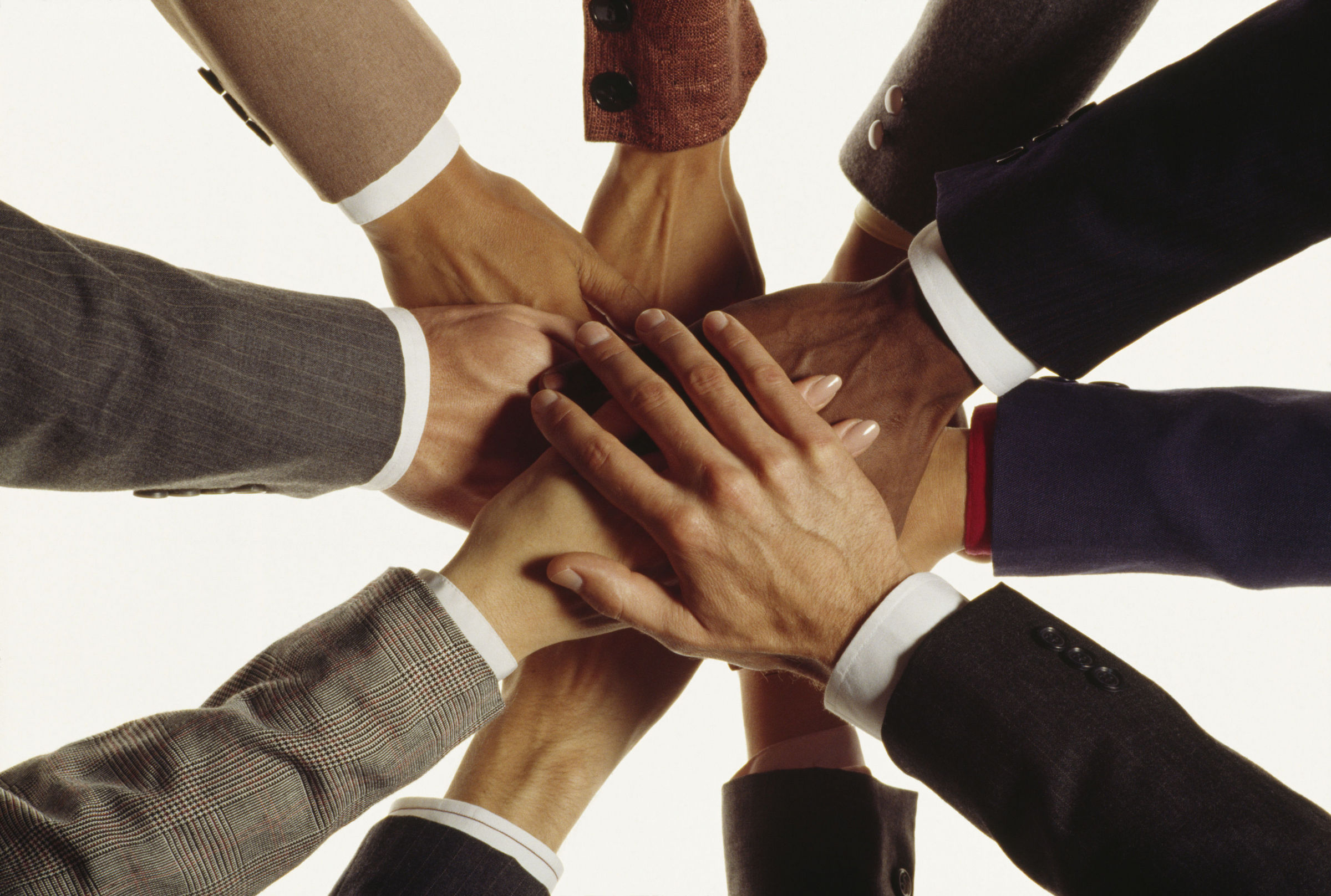 photo of hands in business attire joined making a circle