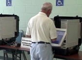 photo of man voting on touchscreen voting machine