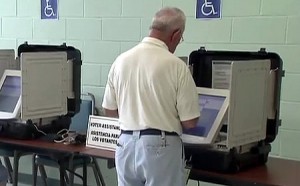 photo of man voting on touchscreen voting machine