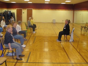 Residents participate in a chair aerobics class in a group studio room at Riderwood retirement community.