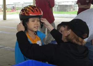 photo of child having bike helmet fitted by woman