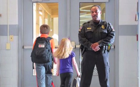 photo of school children and school resource office in school hallway