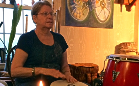 photo of woman playing drums in a drum cirle