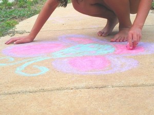 photo of child drawing on sidewalk with chalk