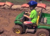 photo of young boy riding atv in mud pit at agricultural fair