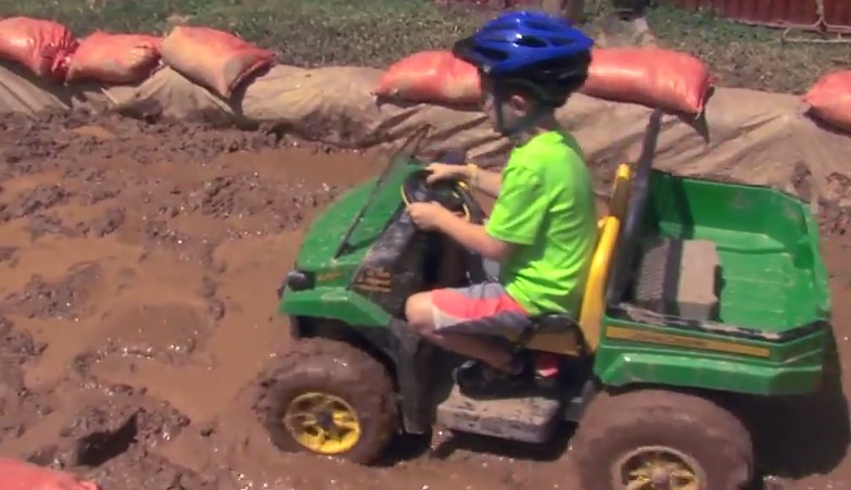 photo of young boy riding atv in mud pit at agricultural fair