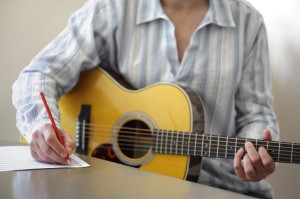 photo of Guitarist musician writing a song on his guitar