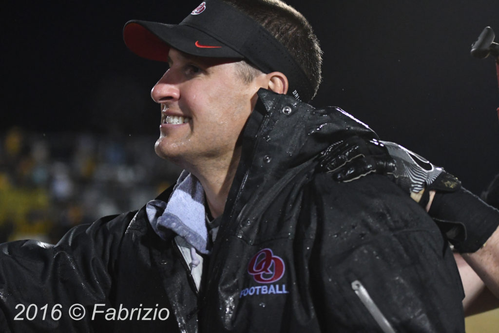 Fresh from his Gatorade bath QO Coach John Kelly is all smiles as he heads to congratulate his team on winning the 4A West Region championship.