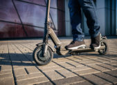 Close up view of legs of man on electric scooter outdoor.