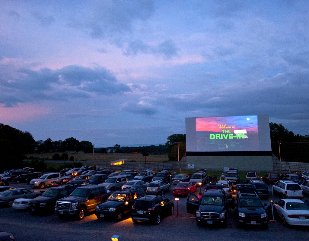 Drive-In Halloween Movies with a bunch of cars on front of the big screen movie projector.