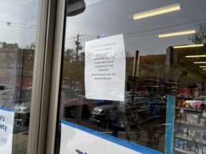 A photo of the Walgreens entry door, which has a piece of paper that announces cash is preferred at this location due to technical issues.